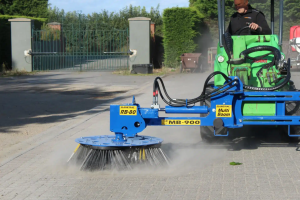 Compact loader using a Slanetrac MB900 MultiBoom Carrier and RB80 hydraulic wire brush to remove weeds and debris from roadside kerbs and gutters.